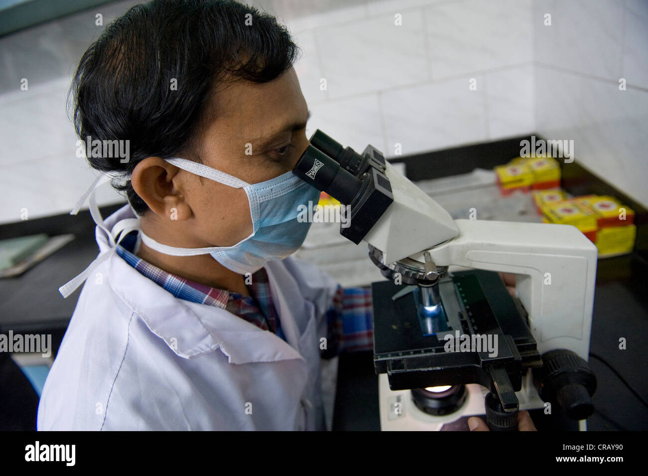 Employee examining a sputum specimen for tuberculosis pathogen under a microscope, St. Thomas Home, Shibpur district, Howrah, Stock Photo