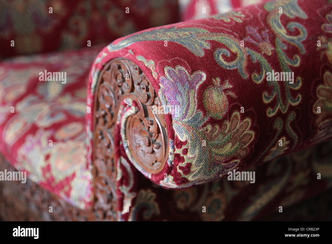 It's a photo of a close up on a old style sofa make of Fabric. The focus is on the armrest. There is a Stylish Patten Stock Photo