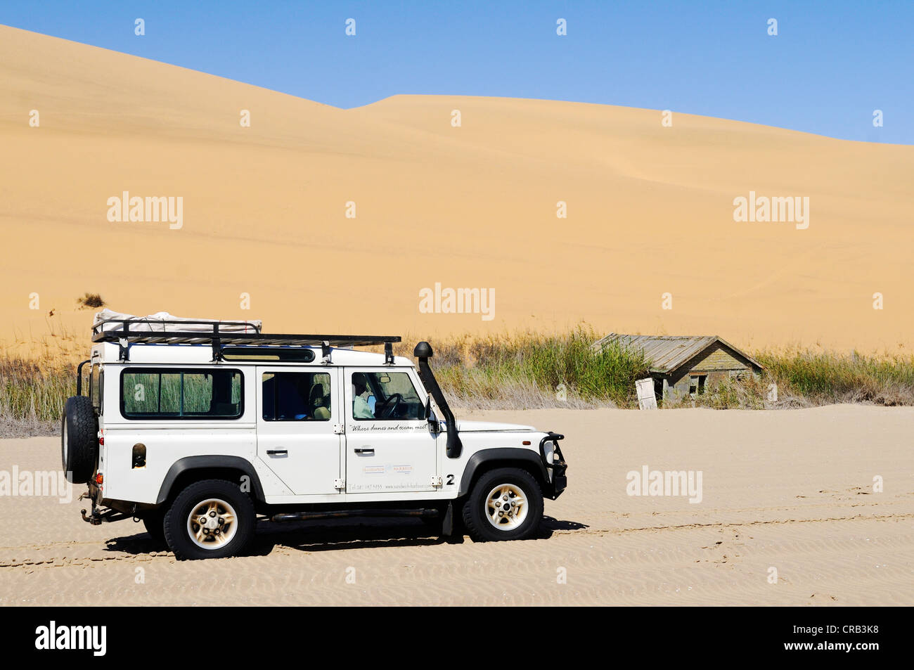 Landrover Defender off-road vehicle and an abandoned wooden hut in the wetlands of Sandwich Harbour,  National Park, part of the Stock Photo
