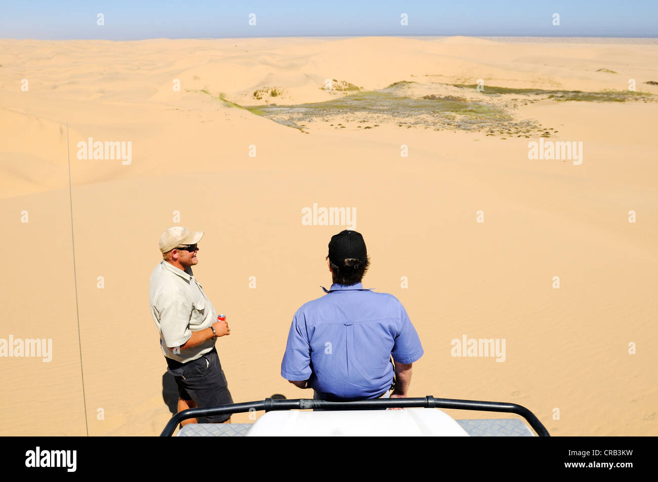 Two men with a Landrover Defender off-road vehicle in the dunes of the  National Park, part of the Namibian Skeleton Coast Stock Photo