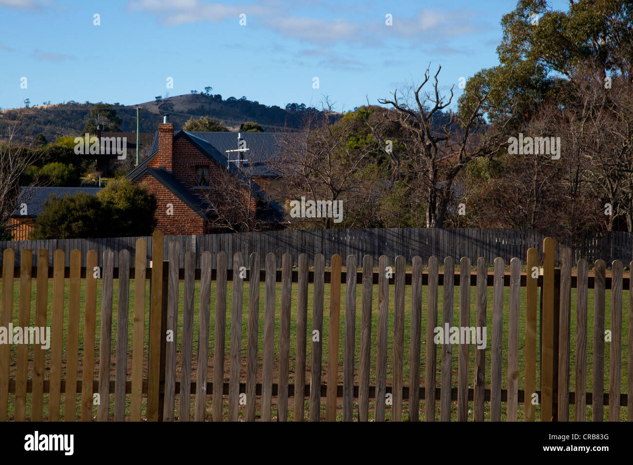 View of house and trees with wooden fence in the foreground, Tasmania, Australia Stock Photo