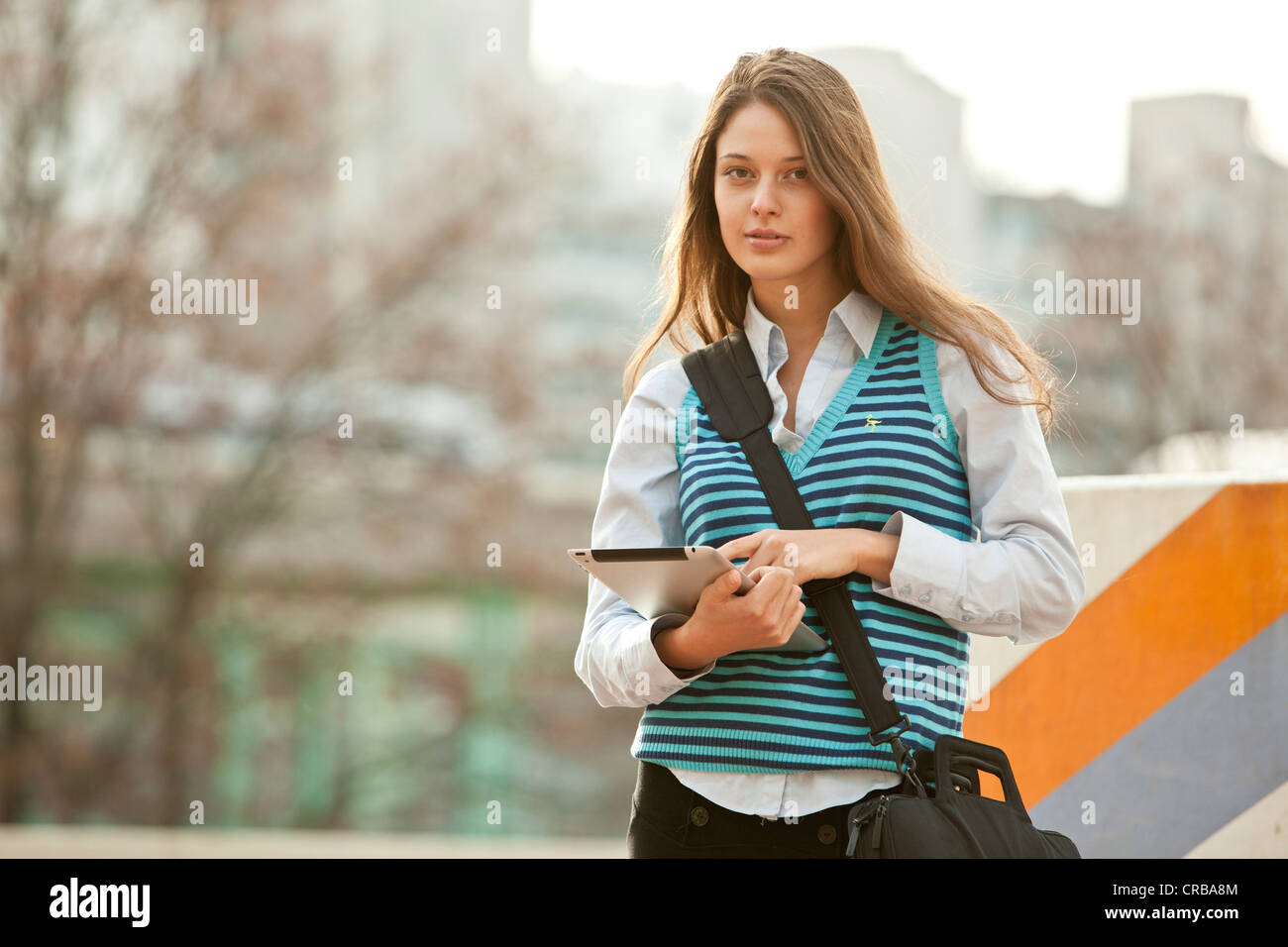 Student on the move with a tablet PC and a shoulder bag Stock Photo