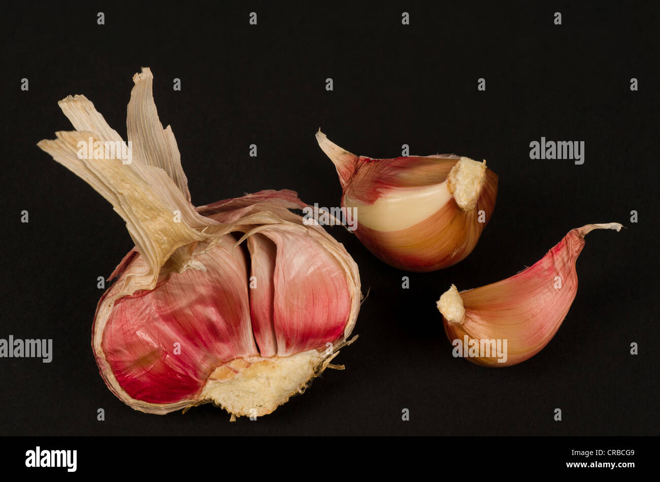 A red garlic bulb and its cloves on black Stock Photo - Alamy
