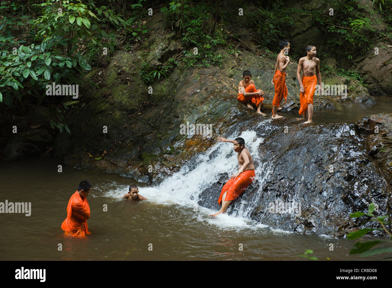 Buddhist monks having a bath in a waterfall in the jungle, Khao Phanom