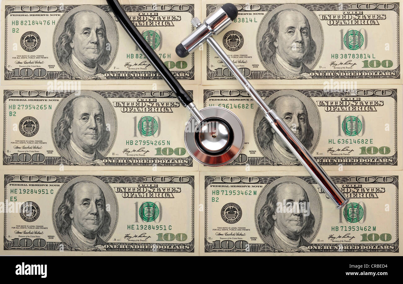 Stethoscope and a reflex hammer on U.S. dollar banknotes, symbolic image of a sick U.S. currency or the increasing cost of Stock Photo