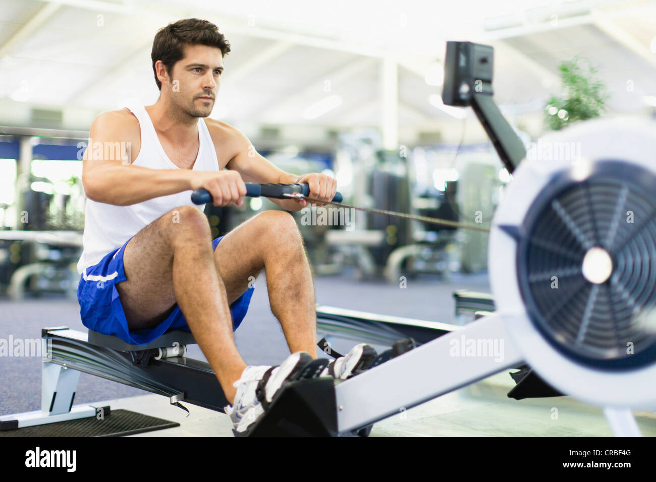 Man using rowing machine in gym Stock Photo