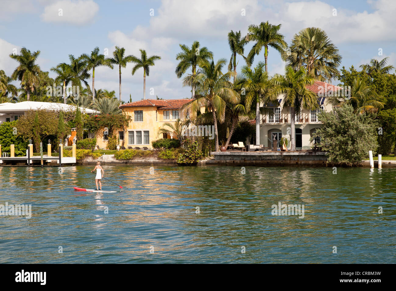 Girl on a surfboard off luxury mansions in Miami, Florida, USA Stock Photo