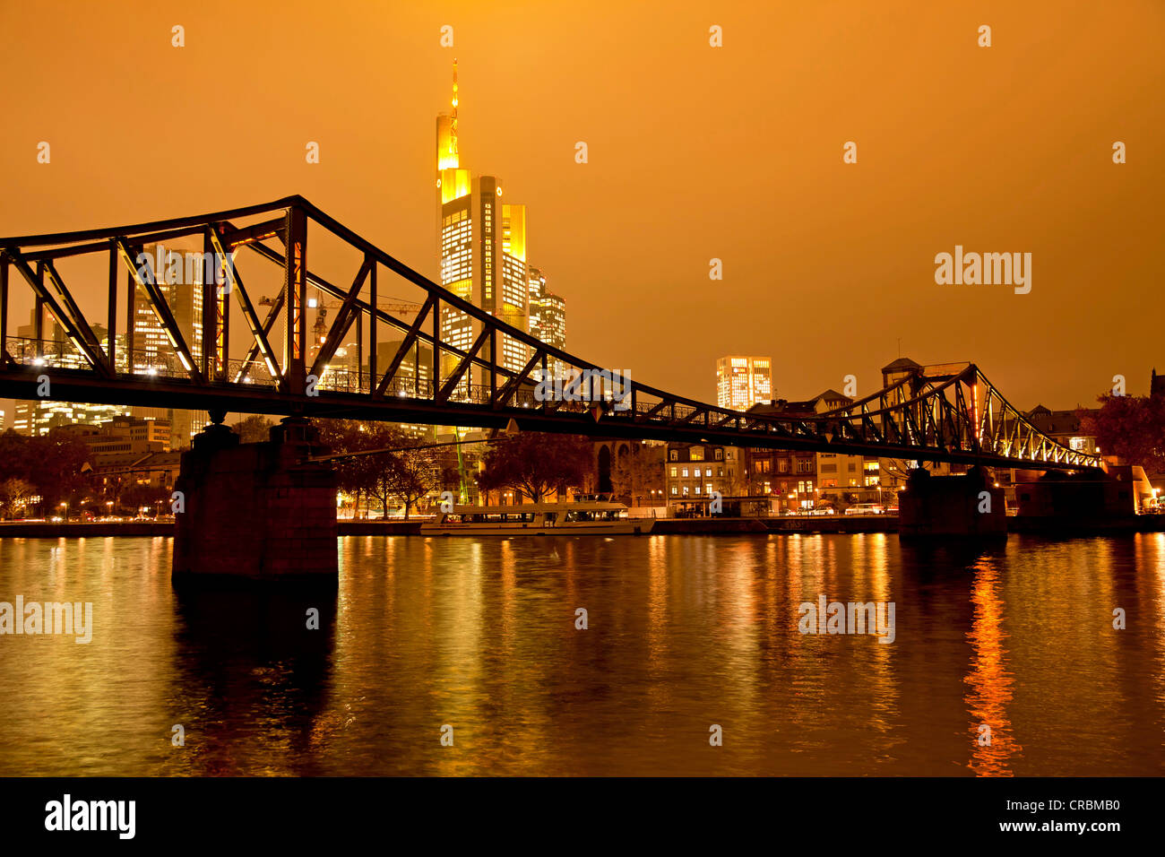 Eiserner Steg Bruecke, bridge over the Main river with the illuminated skyline of Frankfurt at dusk, Frankfurt am Main, Hesse Stock Photo