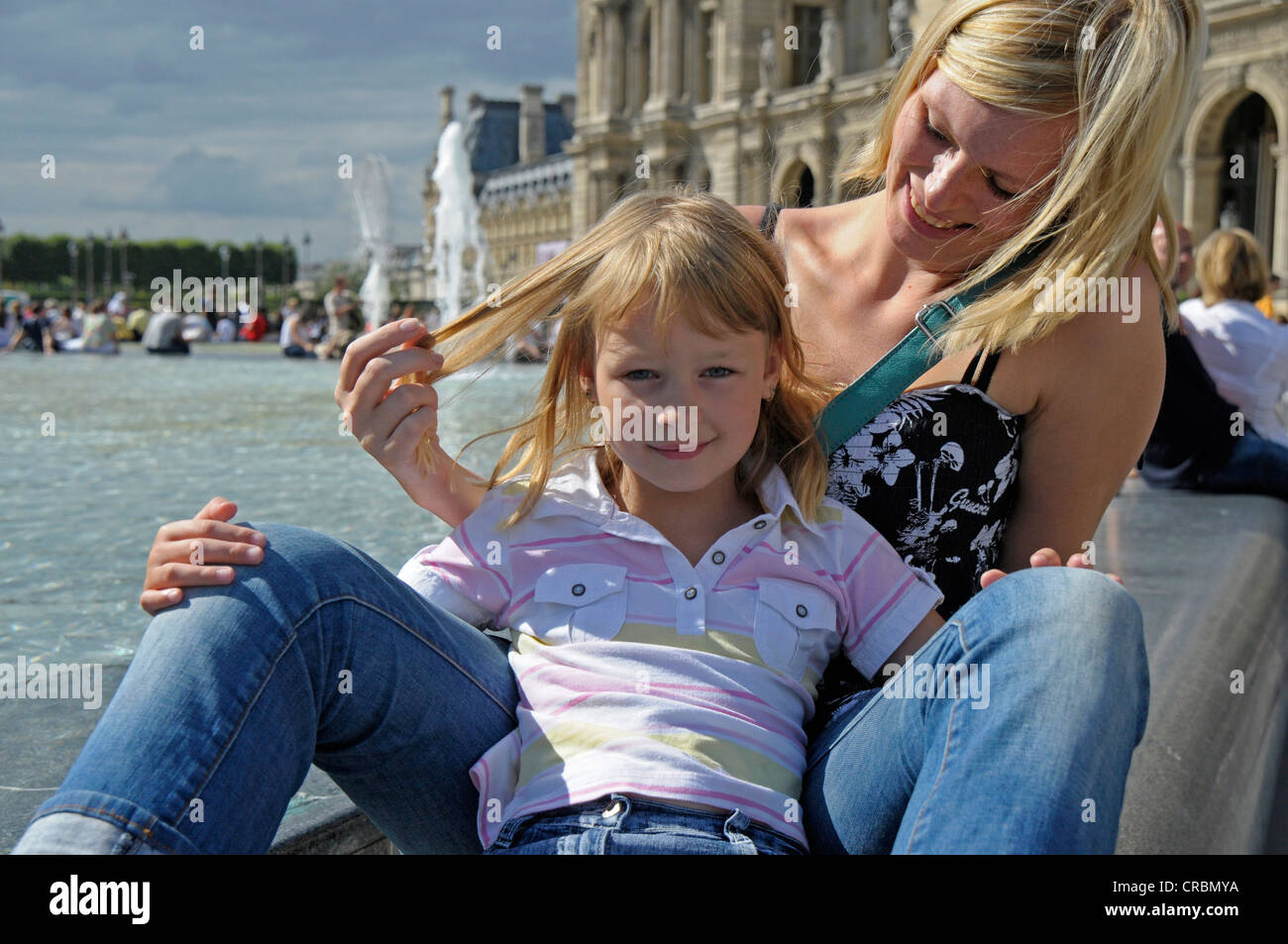Young mother with her daughter on a city trip sitting in front of the Louvre in Paris, France, Europe Stock Photo