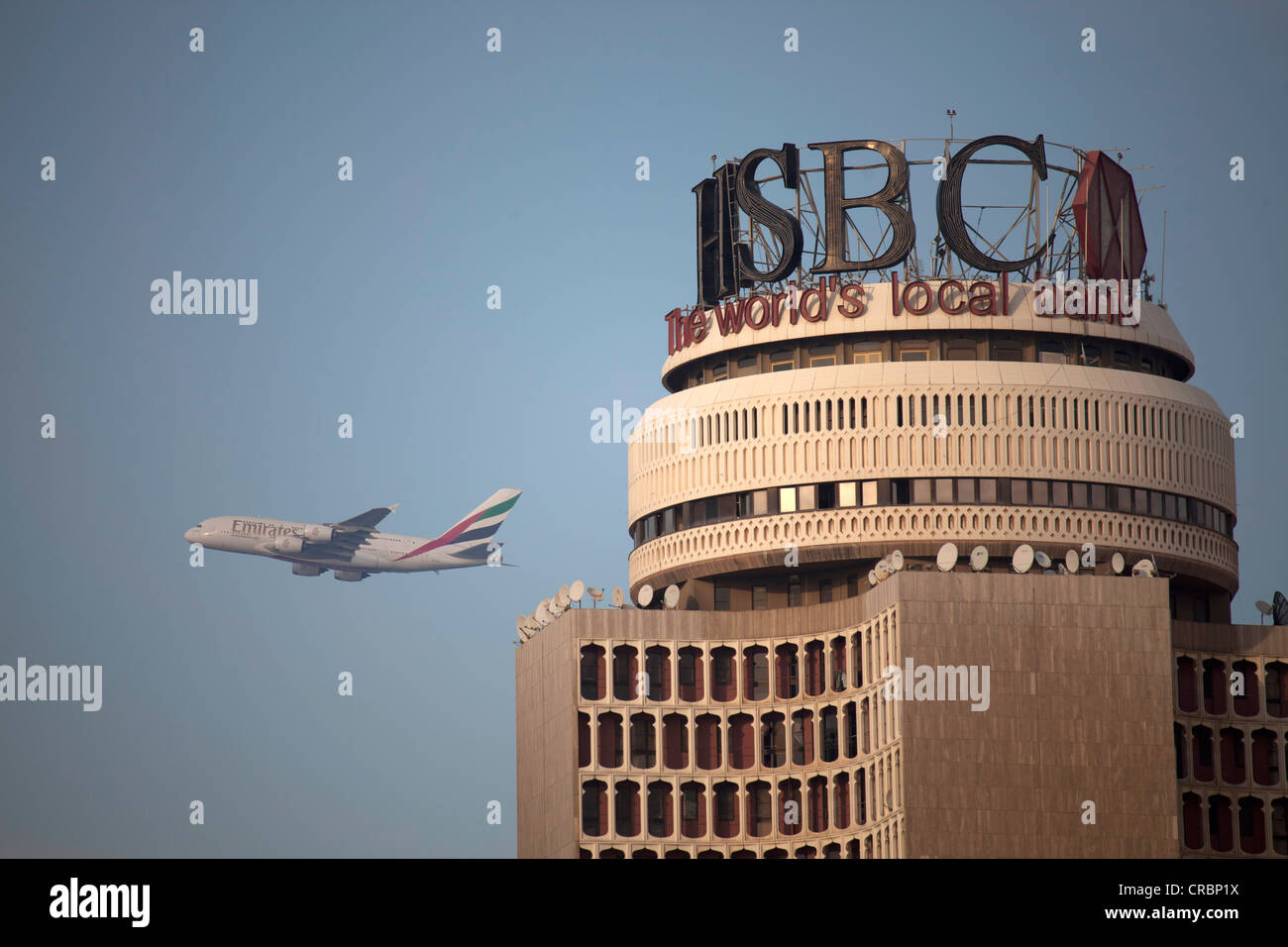 High-rise building with the HSBC bank logo and a starting airplane of the Emirates airline in , United Arab Emirates Stock Photo