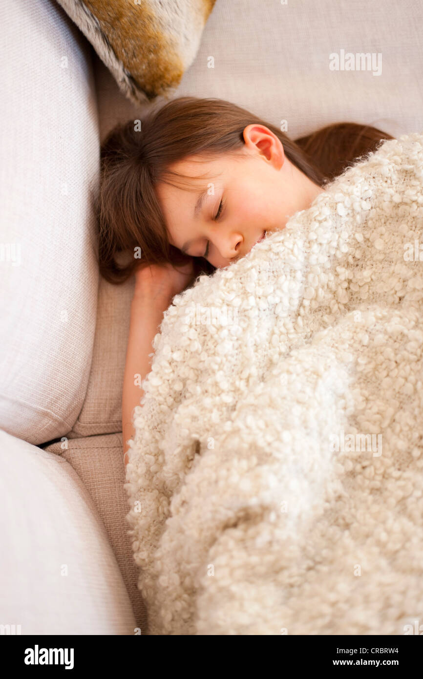 Girl sleeping under blanket on sofa Stock Photo Alamy