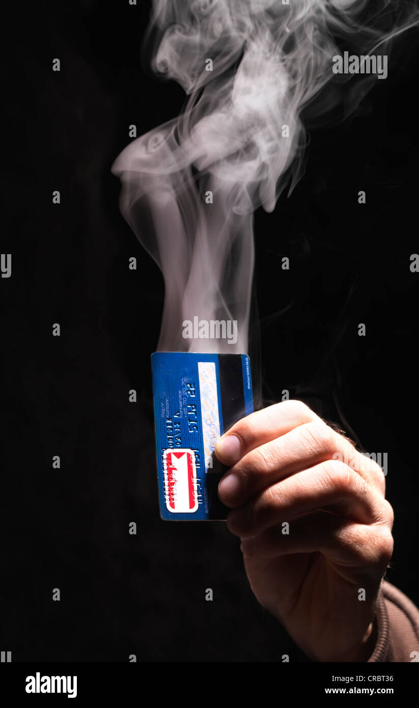 Hand holding smoking credit card Stock Photo