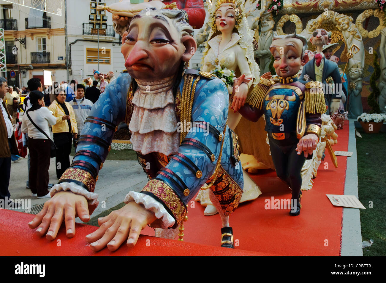 Woman dominating a man, footmen rolling out the red carpet, crude carnival characters and satirical sculptures at a parade, Stock Photo