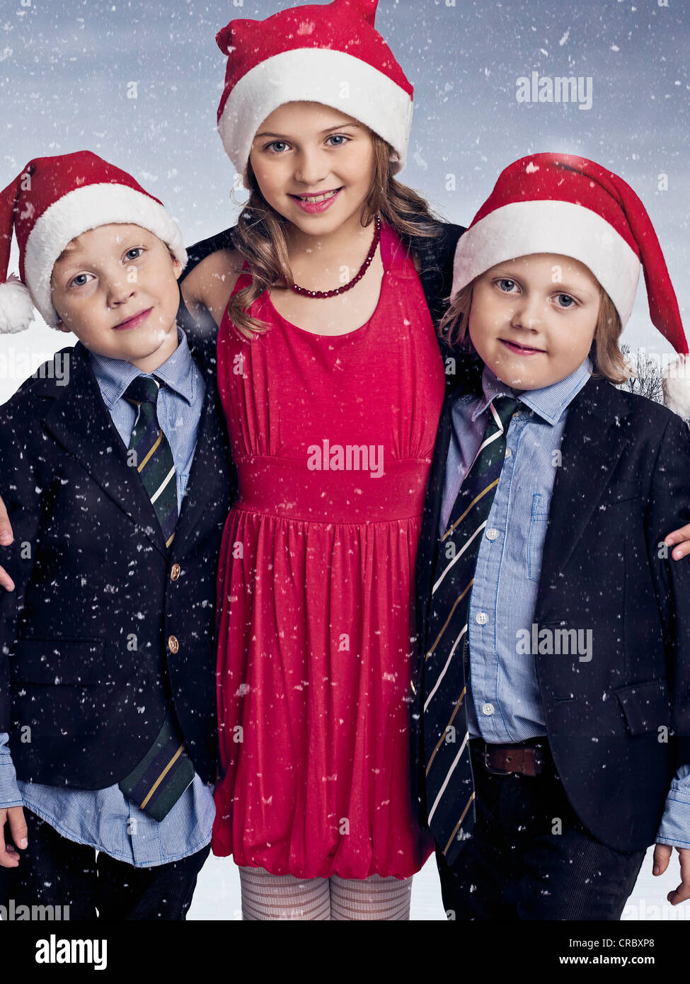 Children wearing Santa hats in snow Stock Photo