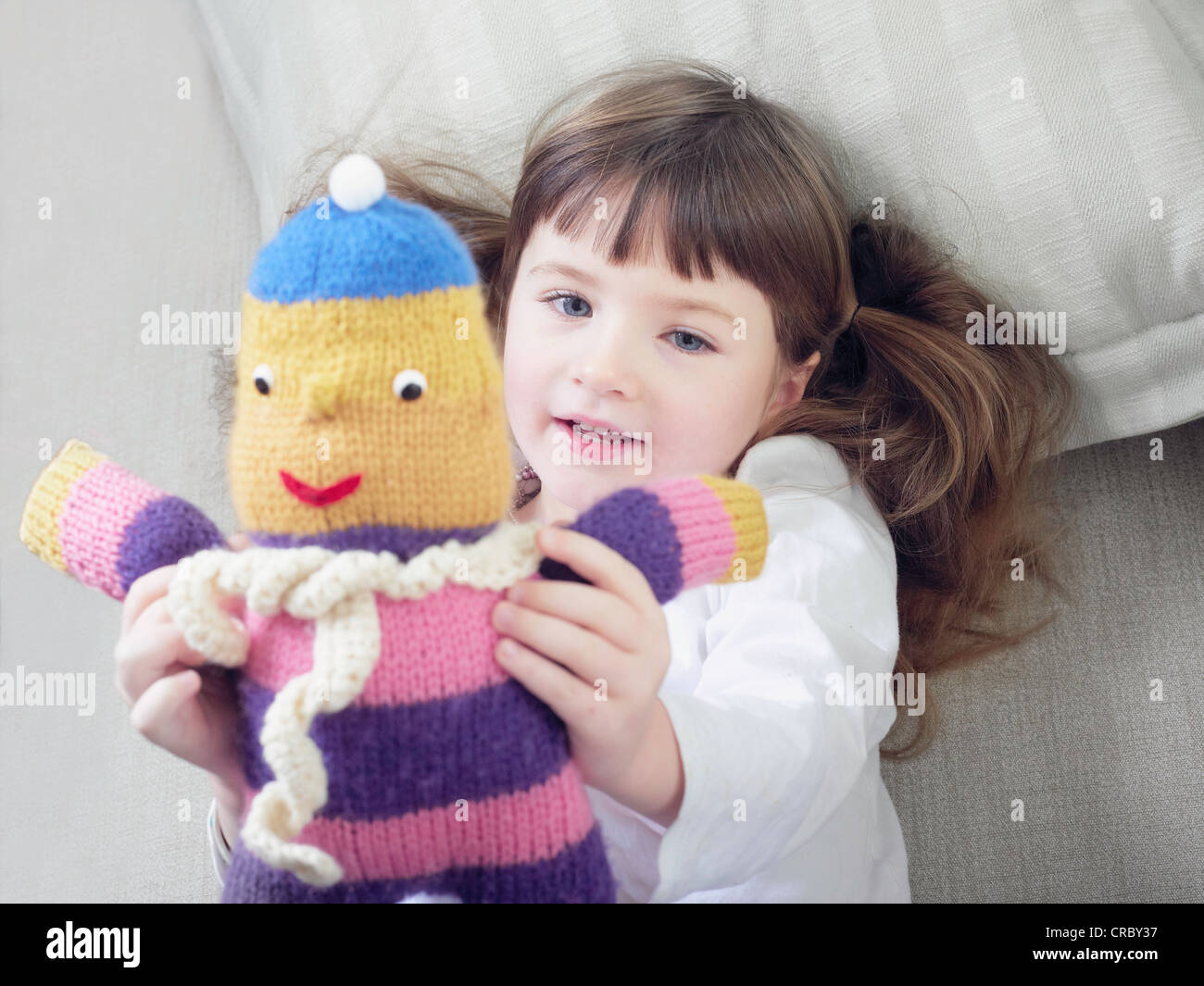 Girl playing with stuffed animal on sofa Stock Photo - Alamy