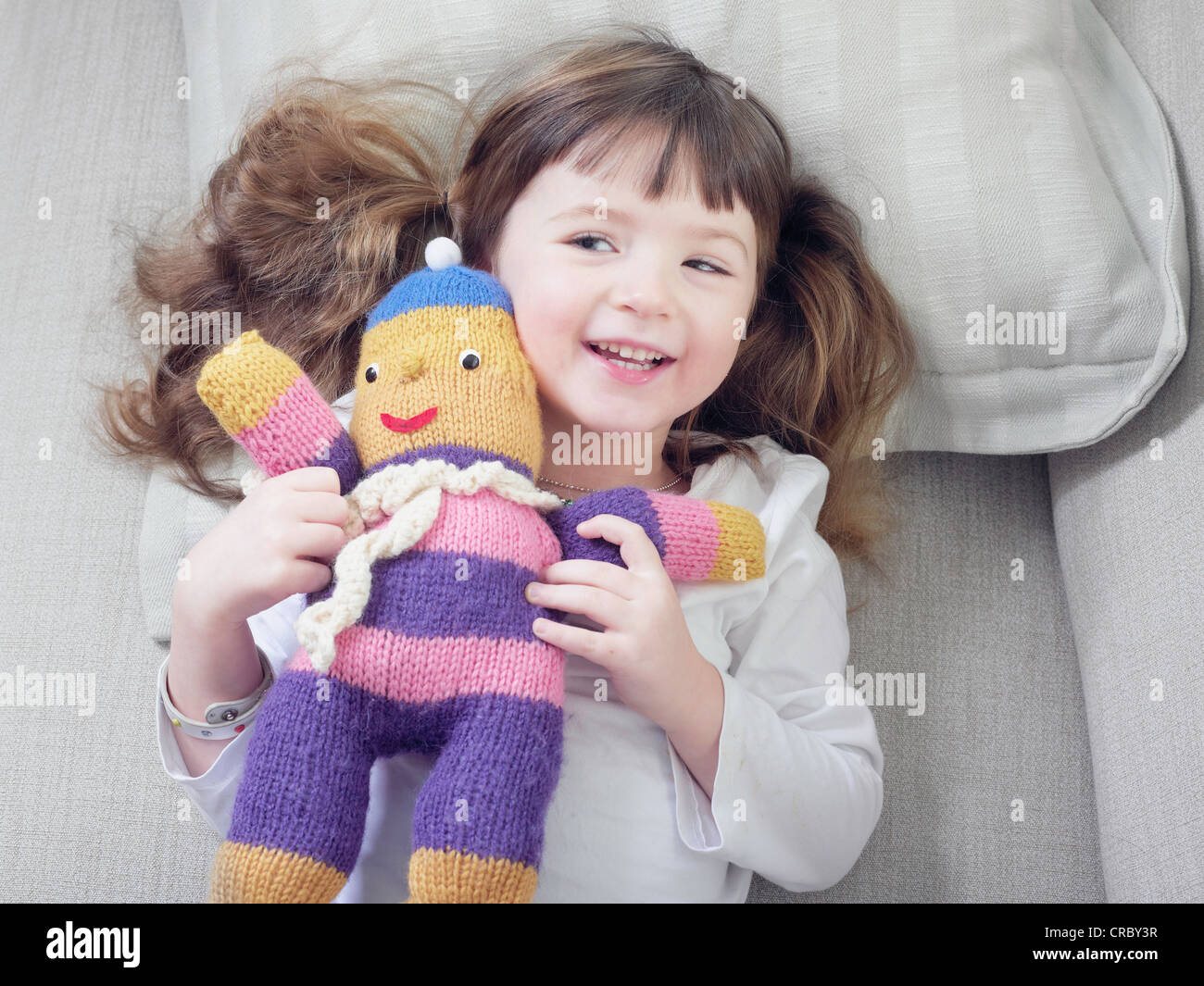 Girl playing with stuffed animal on sofa Stock Photo - Alamy