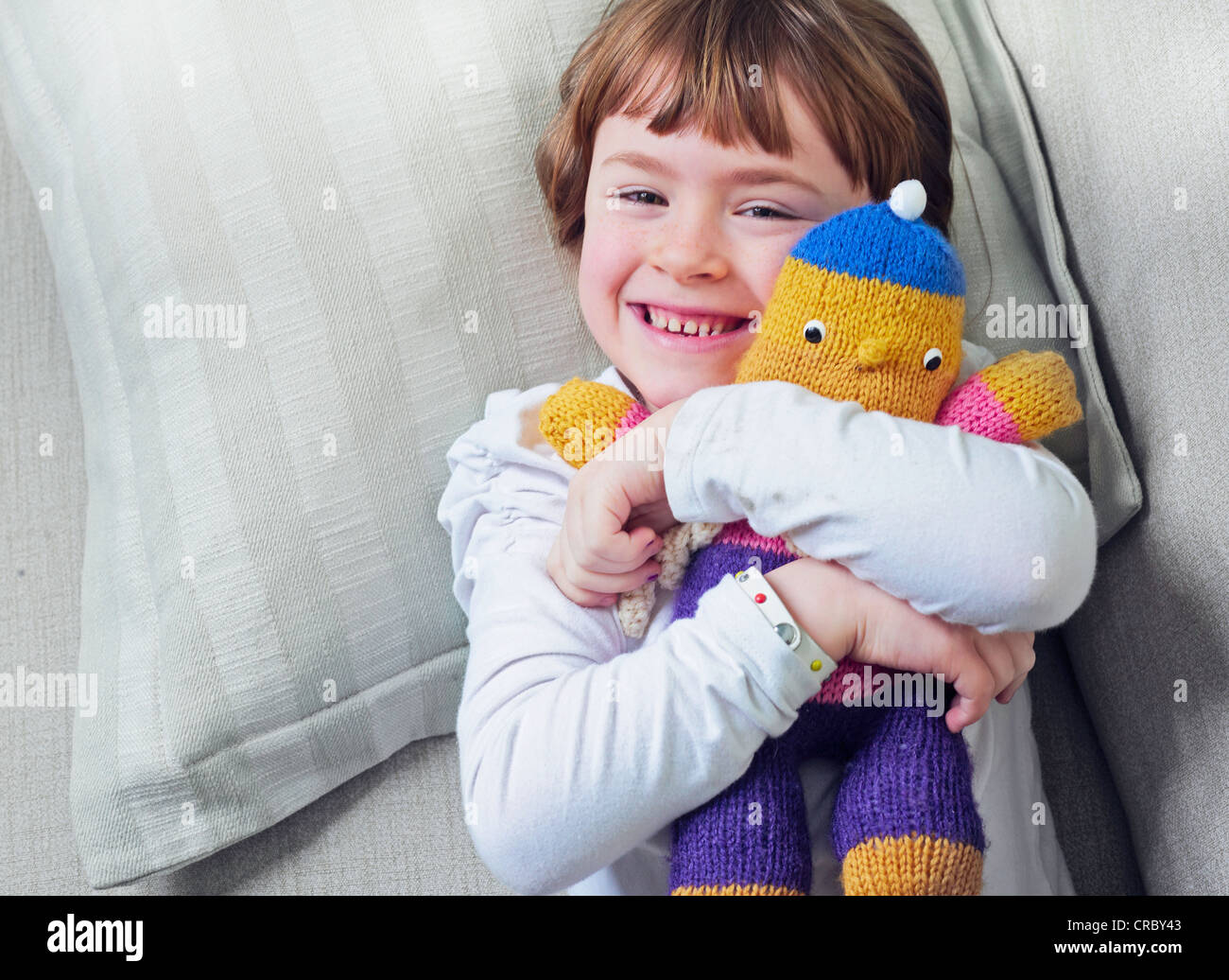 Girl hugging stuffed animal on sofa Stock Photo