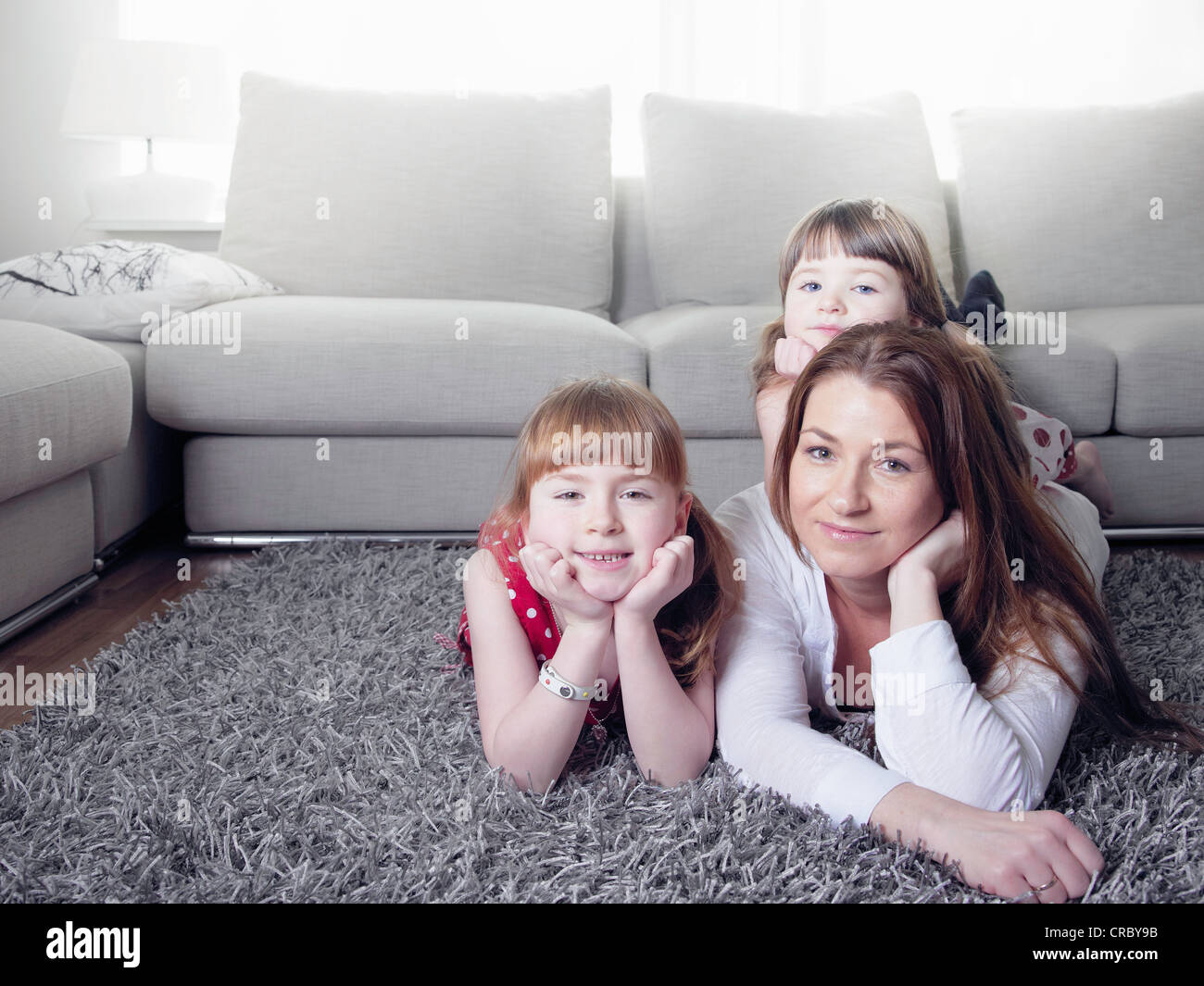 Mother and daughters laying on rug Stock Photo
