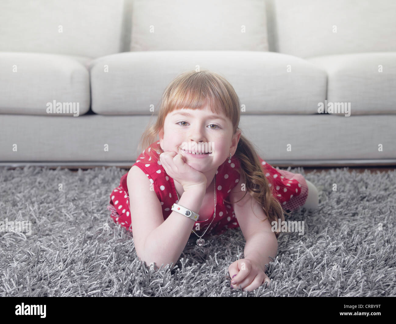 Smiling girl laying on rug Stock Photo