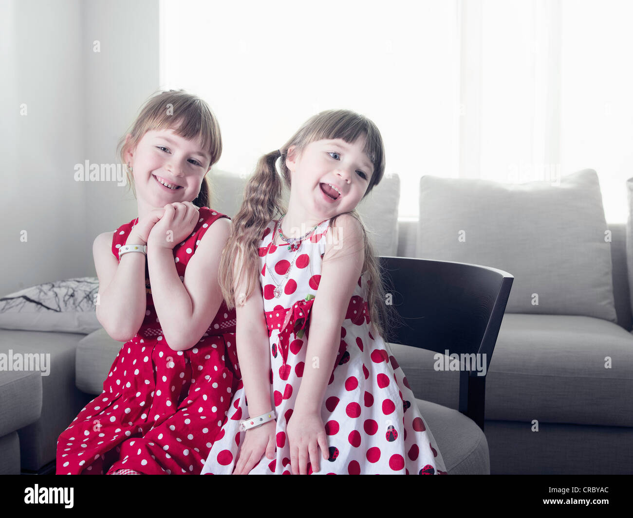 Smiling girls sitting in chair Stock Photo - Alamy