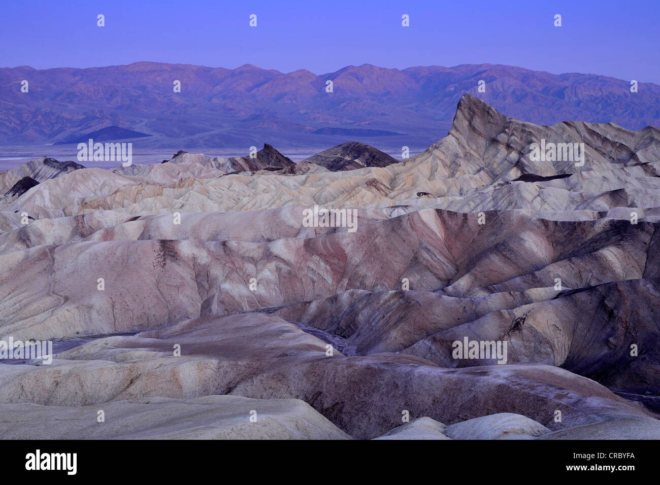 View from Zabriskie Point to Manly Beacon with its eroded rocks coloured by minerals, Panamint Range at back, dawn Stock Photo