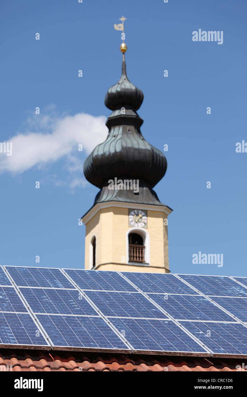 Solar panels on the roof of a house in front of the Church of the Nativity, Frauenried, Irschenberg district, Upper Bavaria Stock Photo