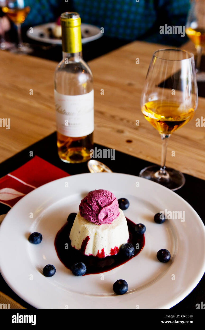 Dessert with blueberries and icecream served on a plate, bottle and glass of wine Stock Photo