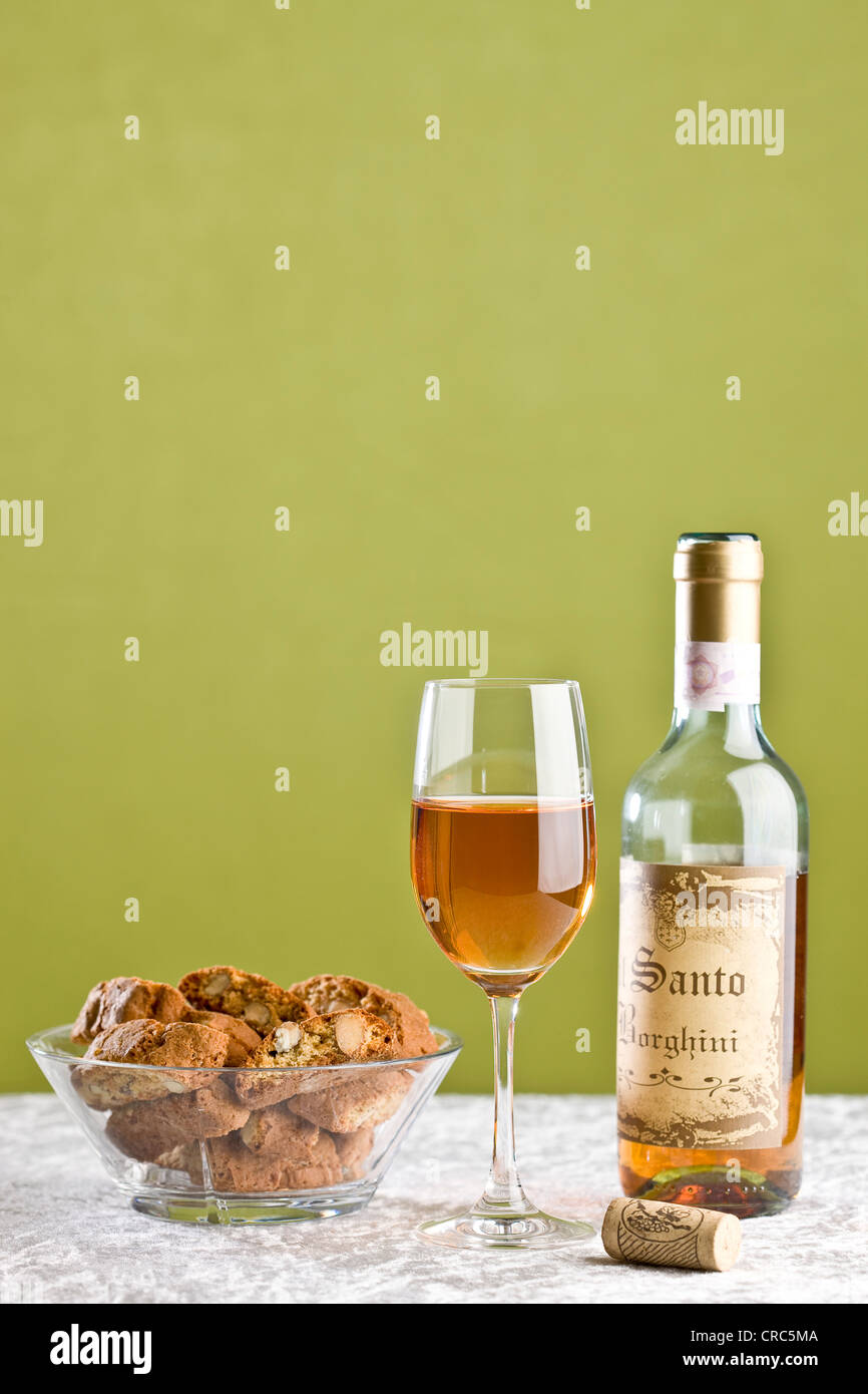Bottle and glass of Vin Santo dessert wine and bowl of almond cookies Stock Photo