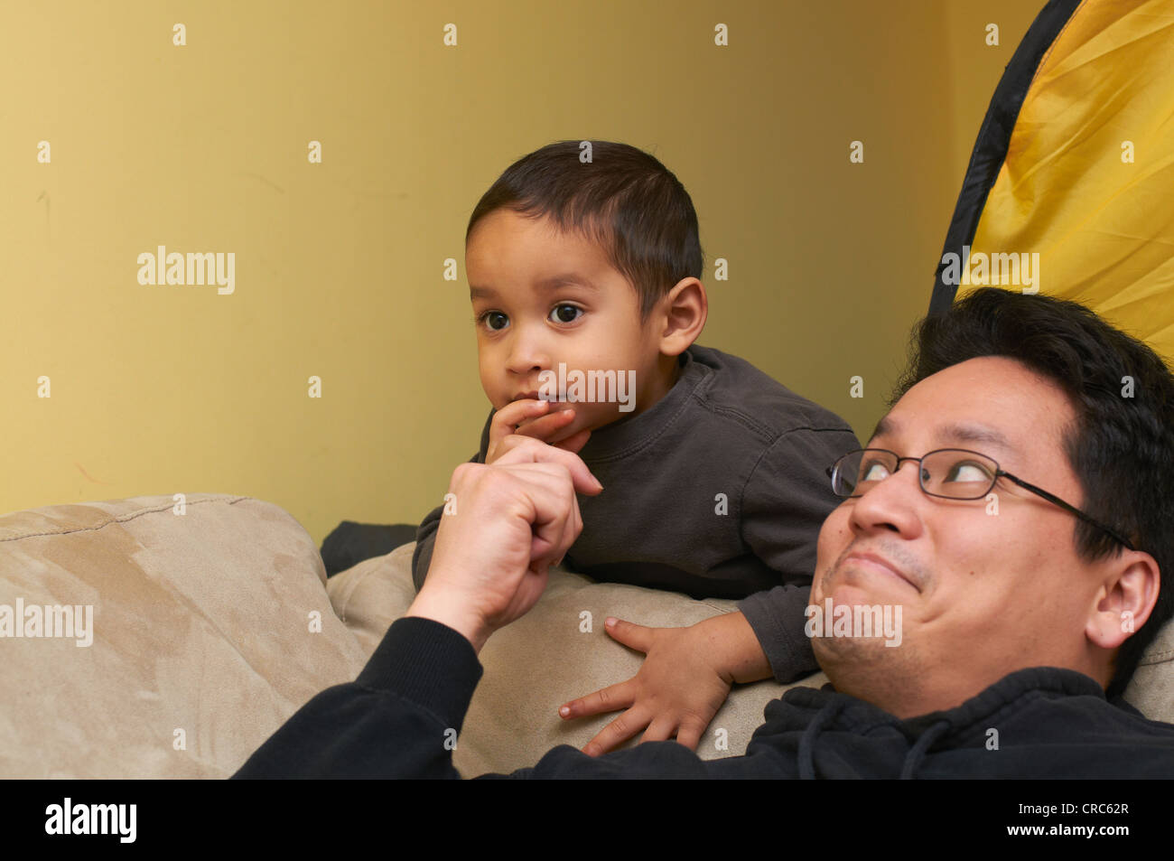 Father and son playing on sofa Stock Photo