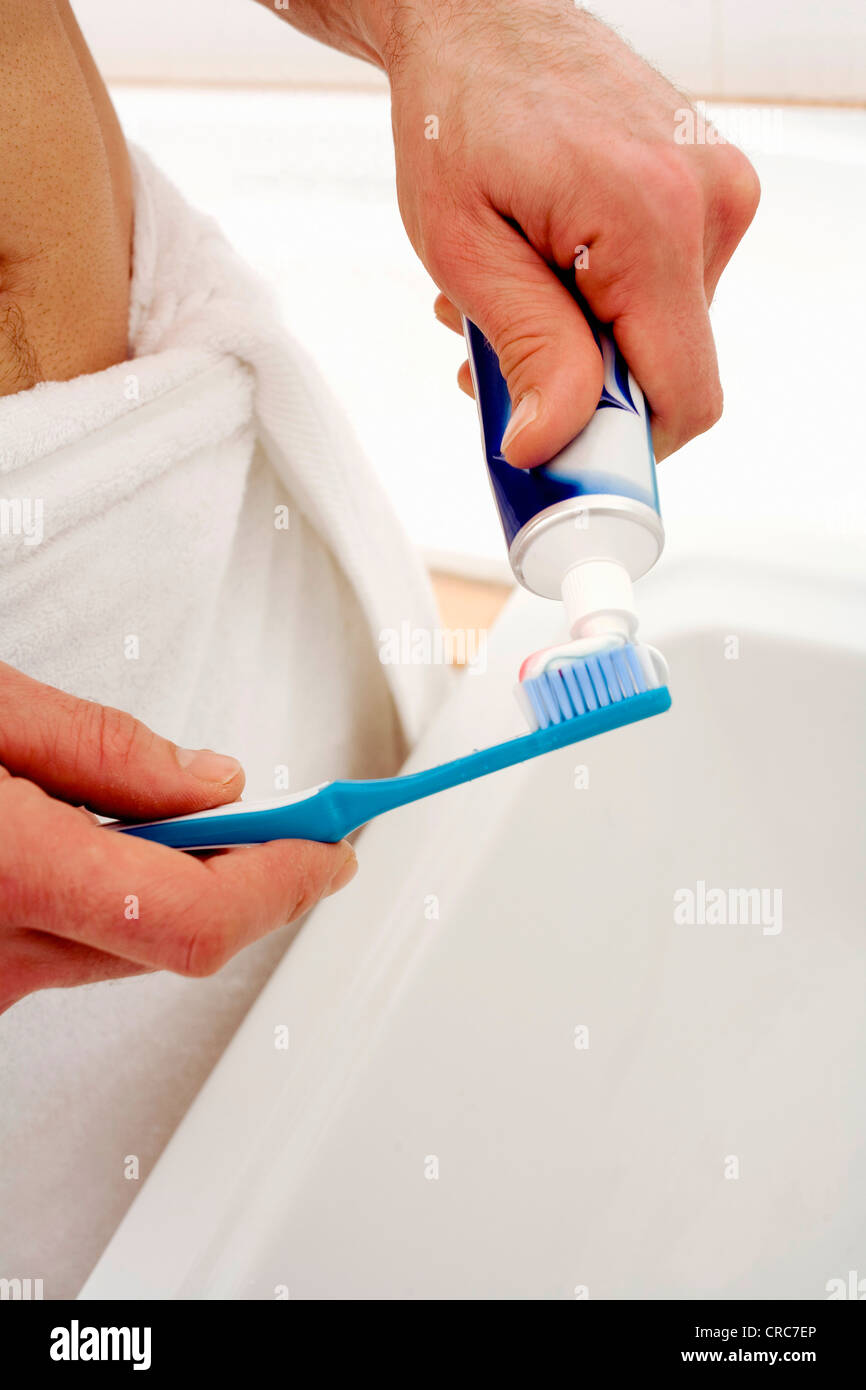 Man squeezing toothpaste onto toothbrush Stock Photo - Alamy