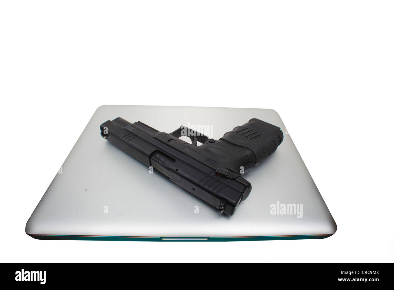 Automatic pistol laid atop an aluminum cased notebook computer Stock Photo