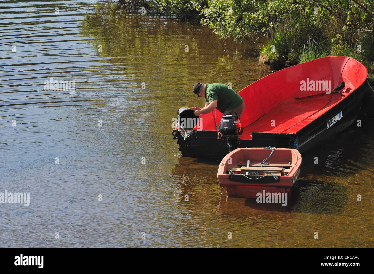 A man bails out a water filled boat after heavy rains over the river Leven in Scotland Stock Photo