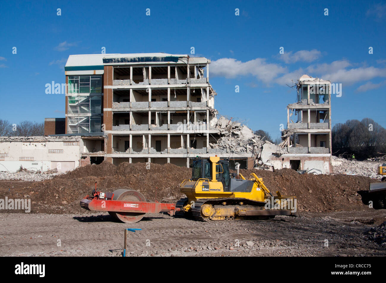 Partly demolished building with mechanical digger clearing away rubble in foreground Cardiff