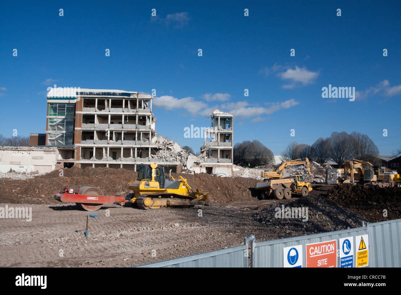Partly demolished building with mechanical digger clearing away rubble in foreground Cardiff