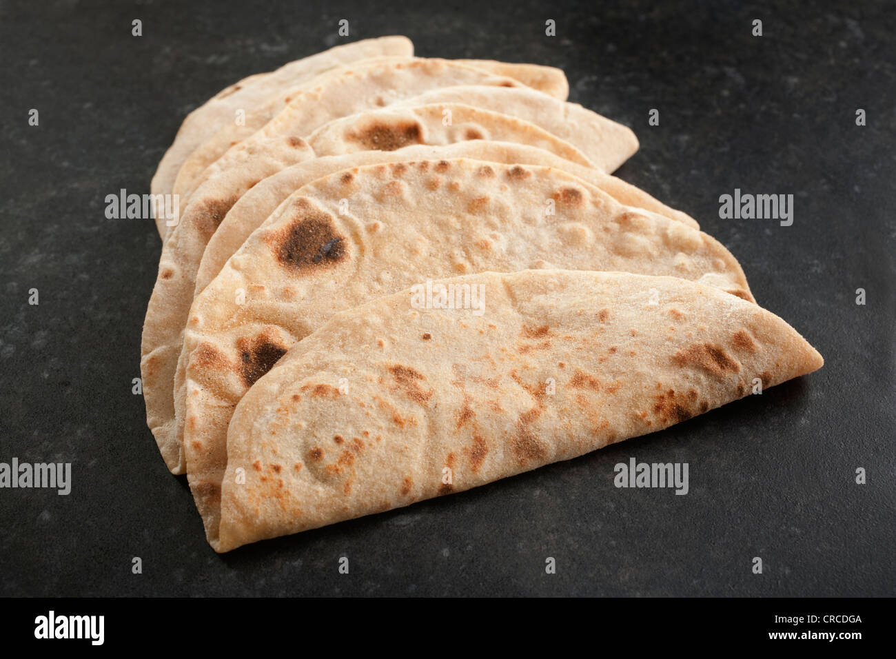 Freshly cooked chapatis or Indian unleavened bread on a dark background. A delicious traditional accompaniment to curry. Stock Photo