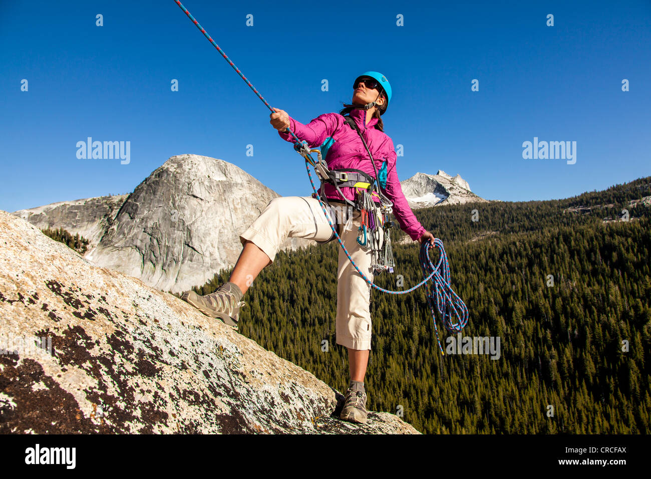 Climber rappelling from the summit after a challenging ascent. Stock Photo