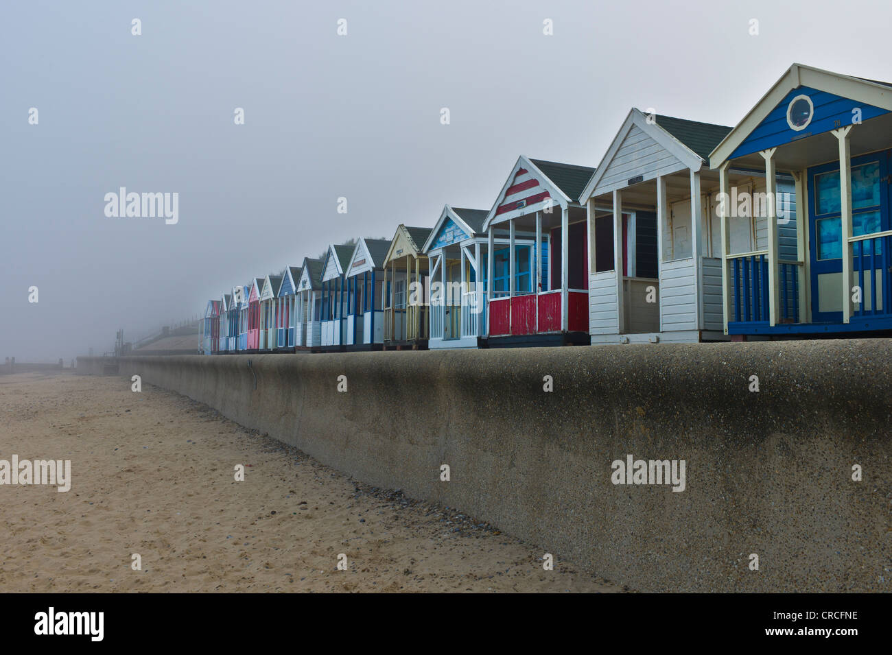 The colourful beach huts at Southwold are isolated from the surroundings by a thick sea fret or fog. Stock Photo