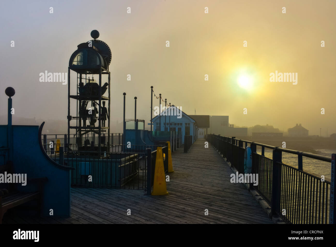 Water powered clock on Southwold pier in a thick sea fret as the sun breaks through Stock Photo