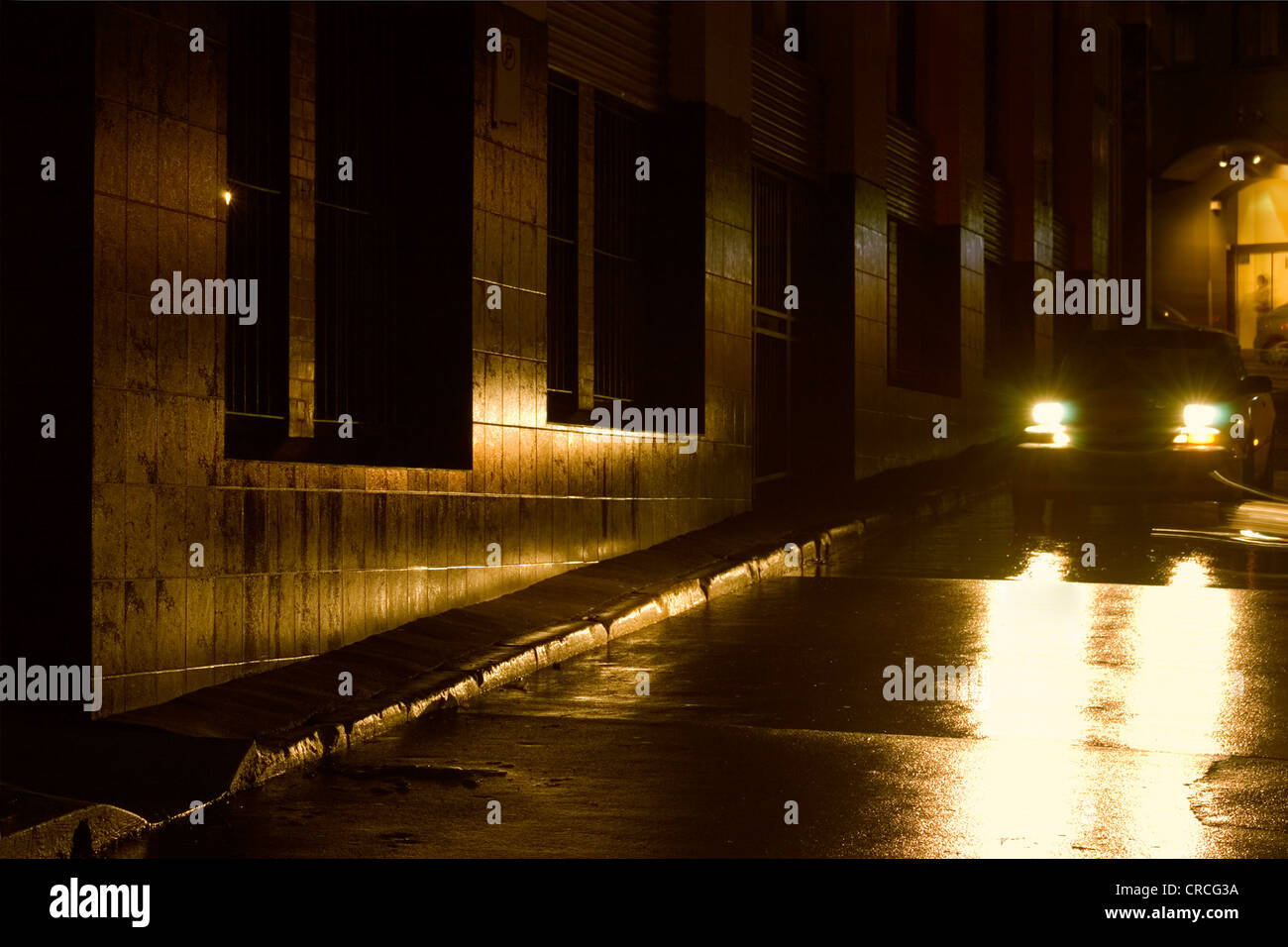 Car headlights reflecting on wet city street Stock Photo