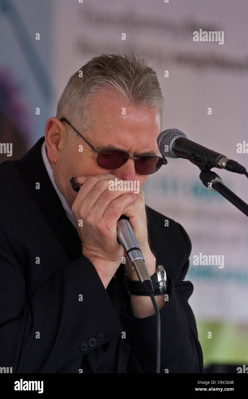 Musician playing blues harmoica into microphone on stage, Mick Ridgeway's Mojo Hand Stock Photo