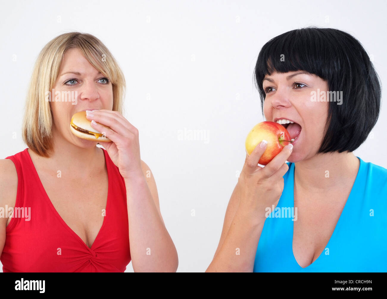 two women eating burger and apple Stock Photo