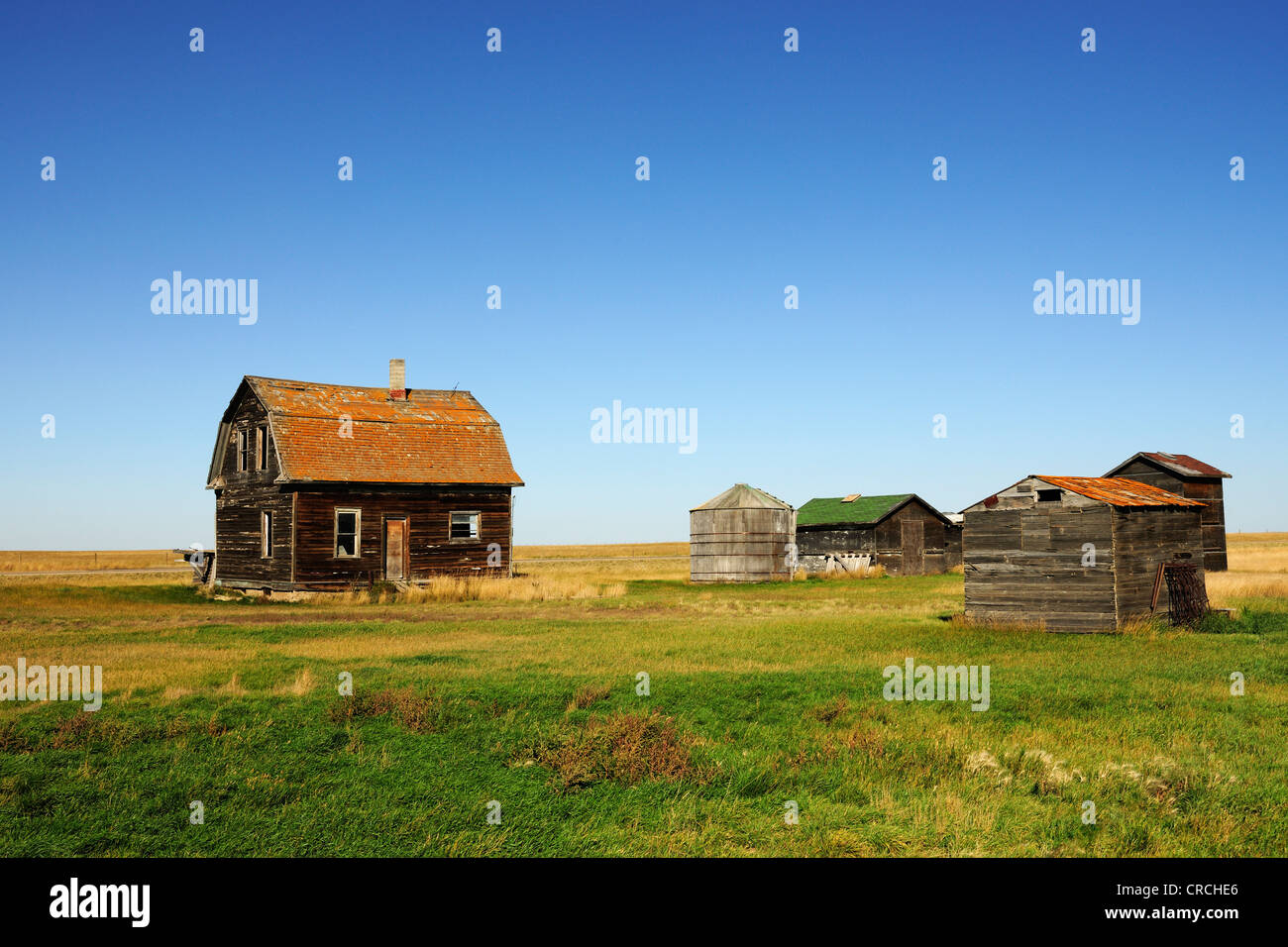 Old abandoned house with barn and grain silos in the Prairies, Saskatchewan, Canada Stock Photo