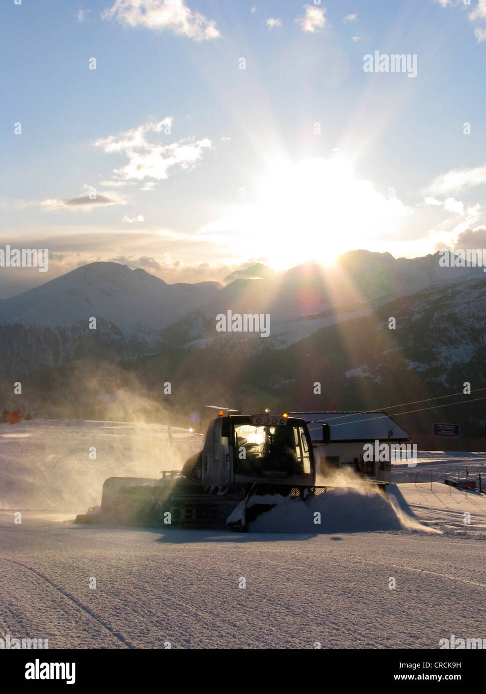 Snow Cat in snowy mountain scenery of a skiing area preparing piste in the evening sun, Italy, Suedtirol, Sarntal, Sarentino, Reinswald Stock Photo