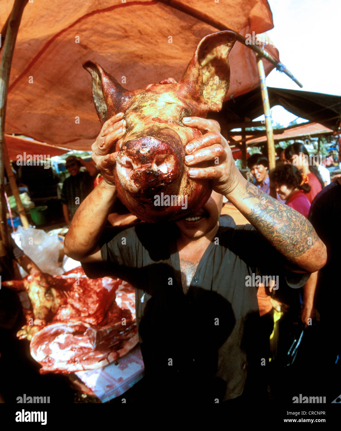 saturday market in the village of Tomahon. A butcher with newly slaughtered pig head, Indonesia, Sulawesi Stock Photo