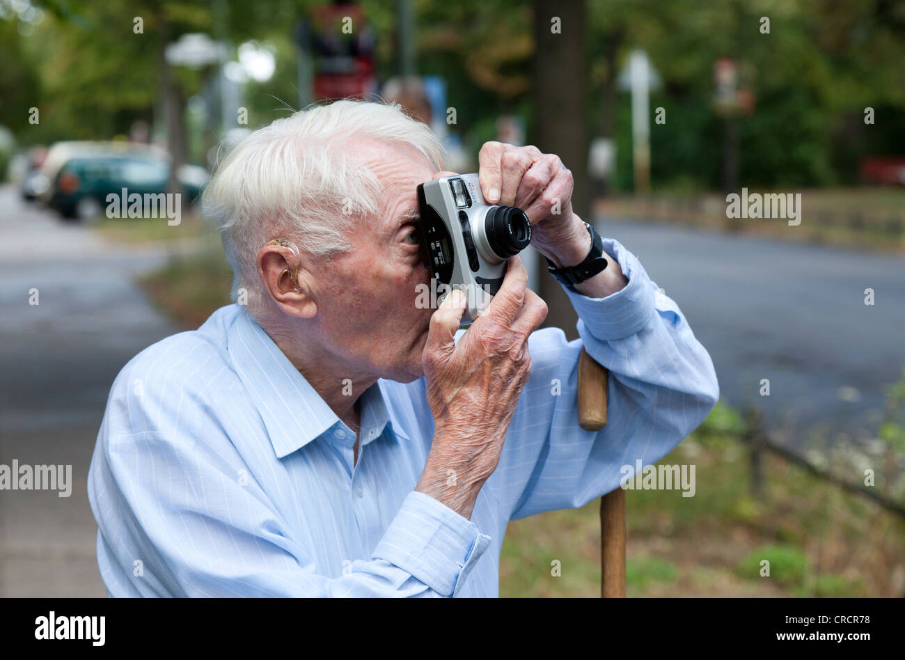 Senior citizen looking through a camera, taking photos Stock Photo