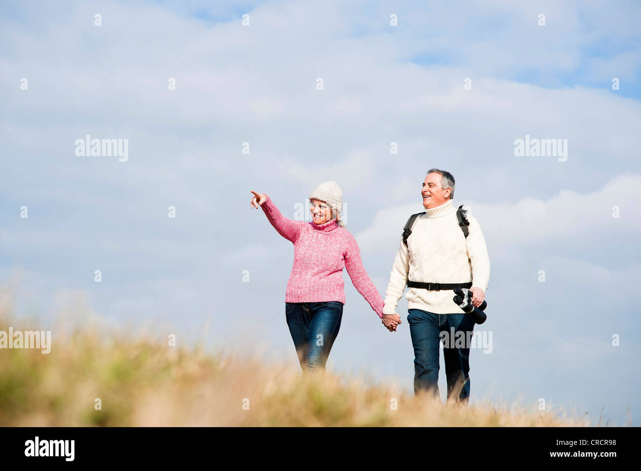Couple walking hand in hand in meadow Stock Photo