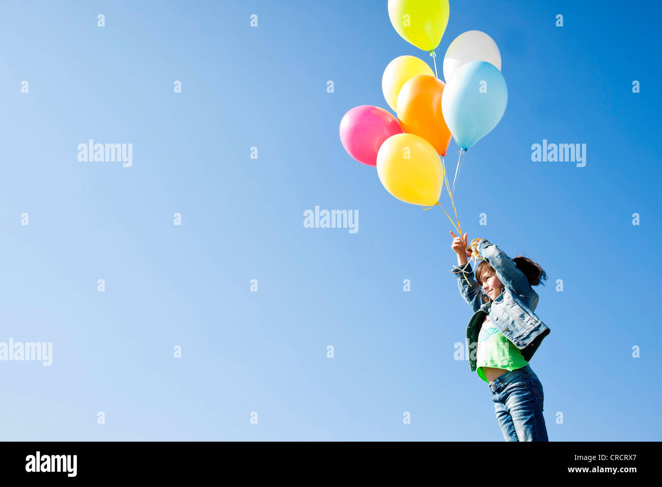 Girl standing with balloons under blue sky Stock Photo - Alamy