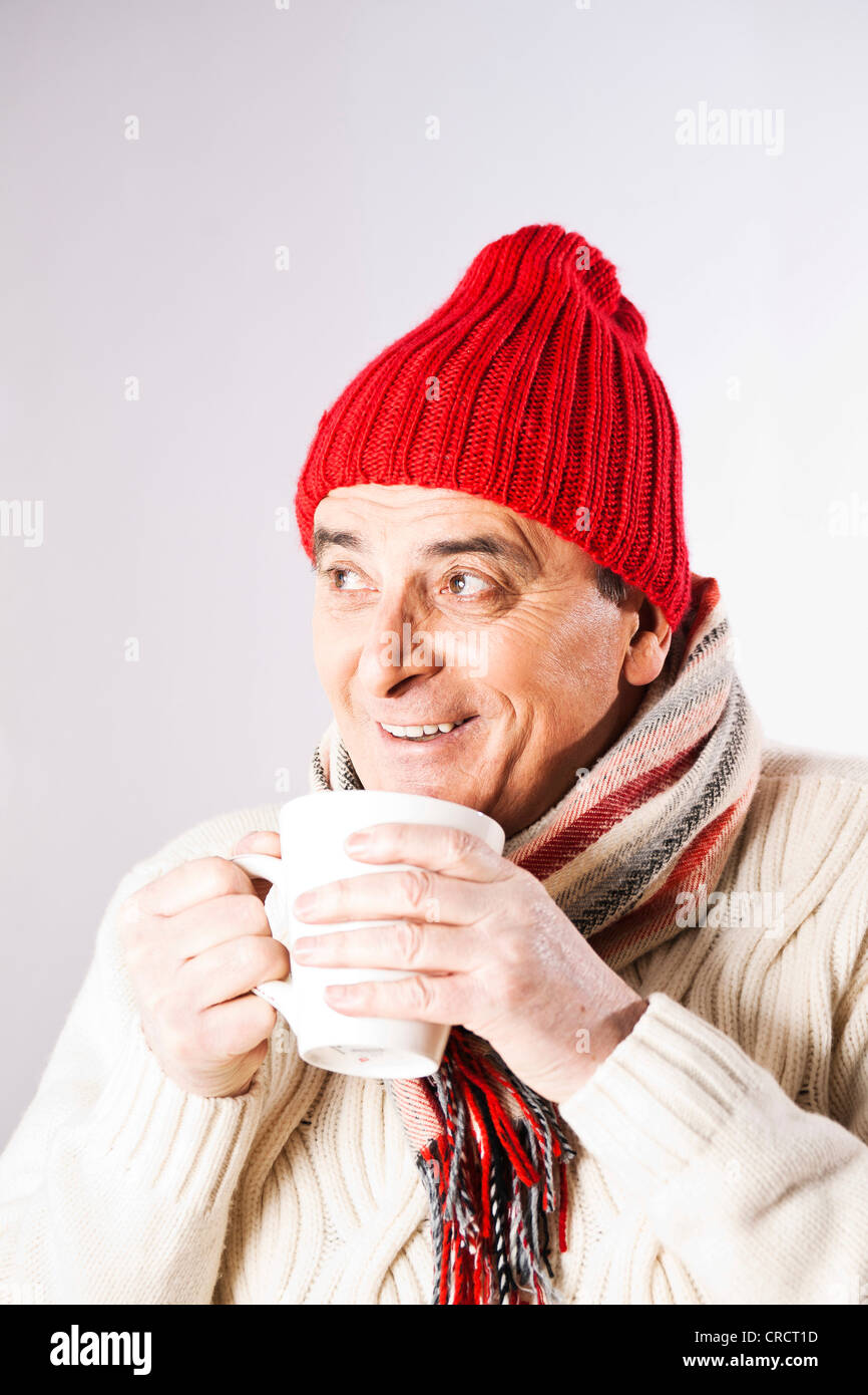 Happy senior man in winter clothes drinking cup of tea Stock Photo