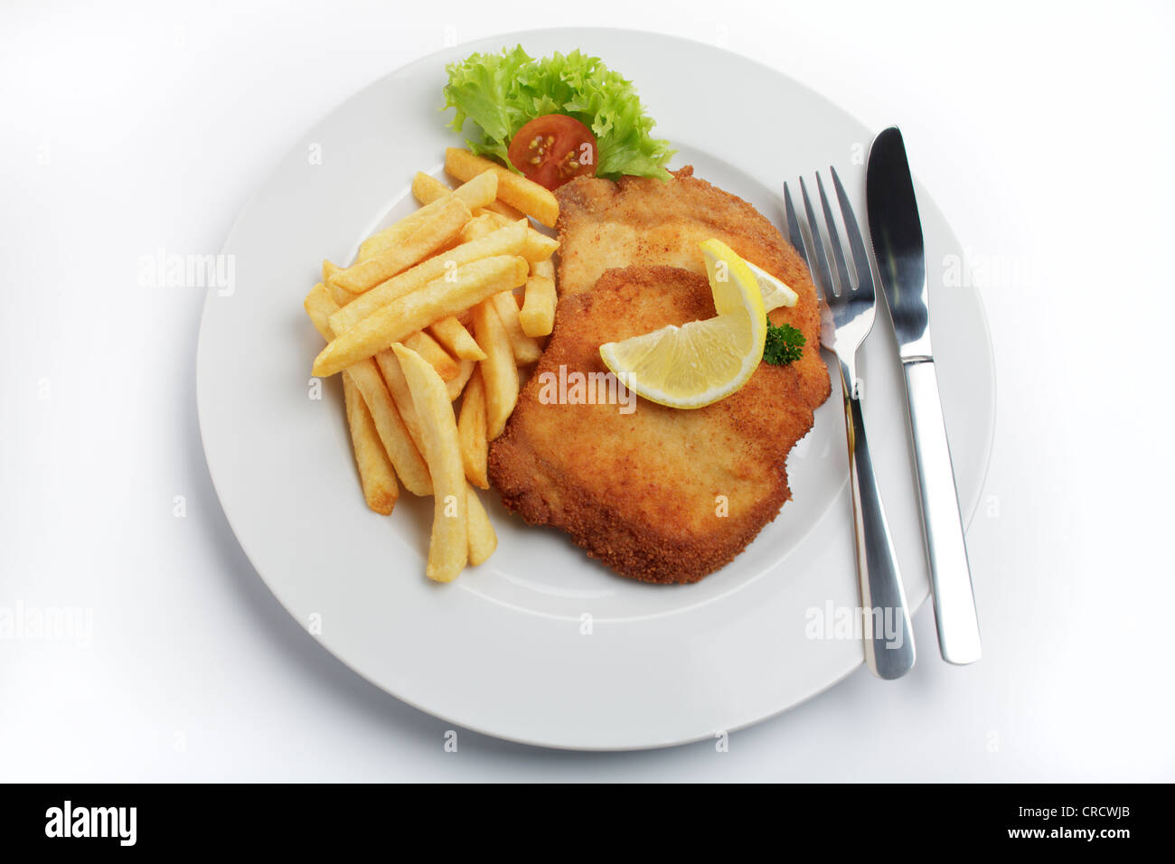 Breaded pork escalope Viennese style with lemon slice and French fries Stock Photo