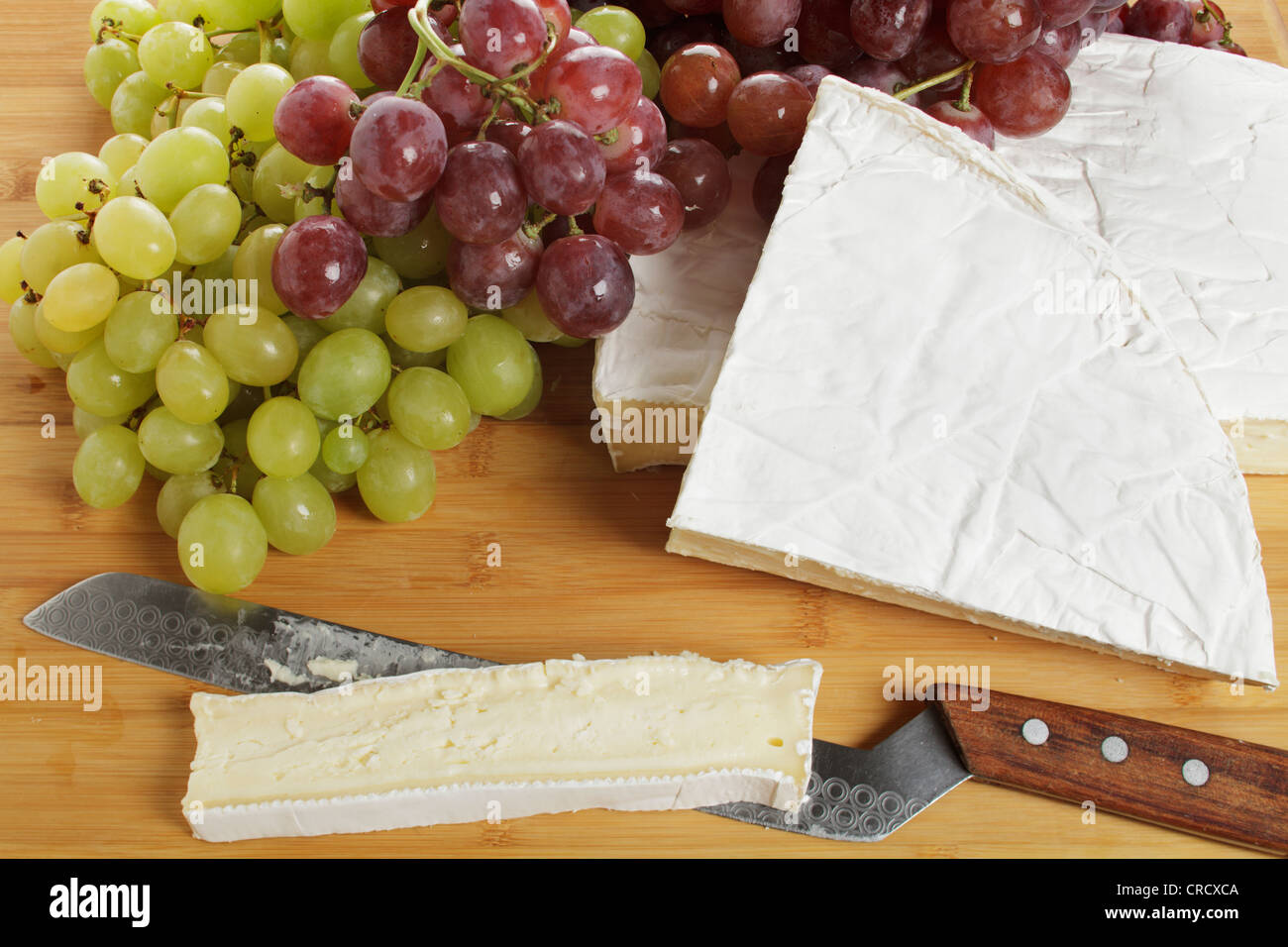Brie with grapes and a cheese knife Stock Photo Alamy